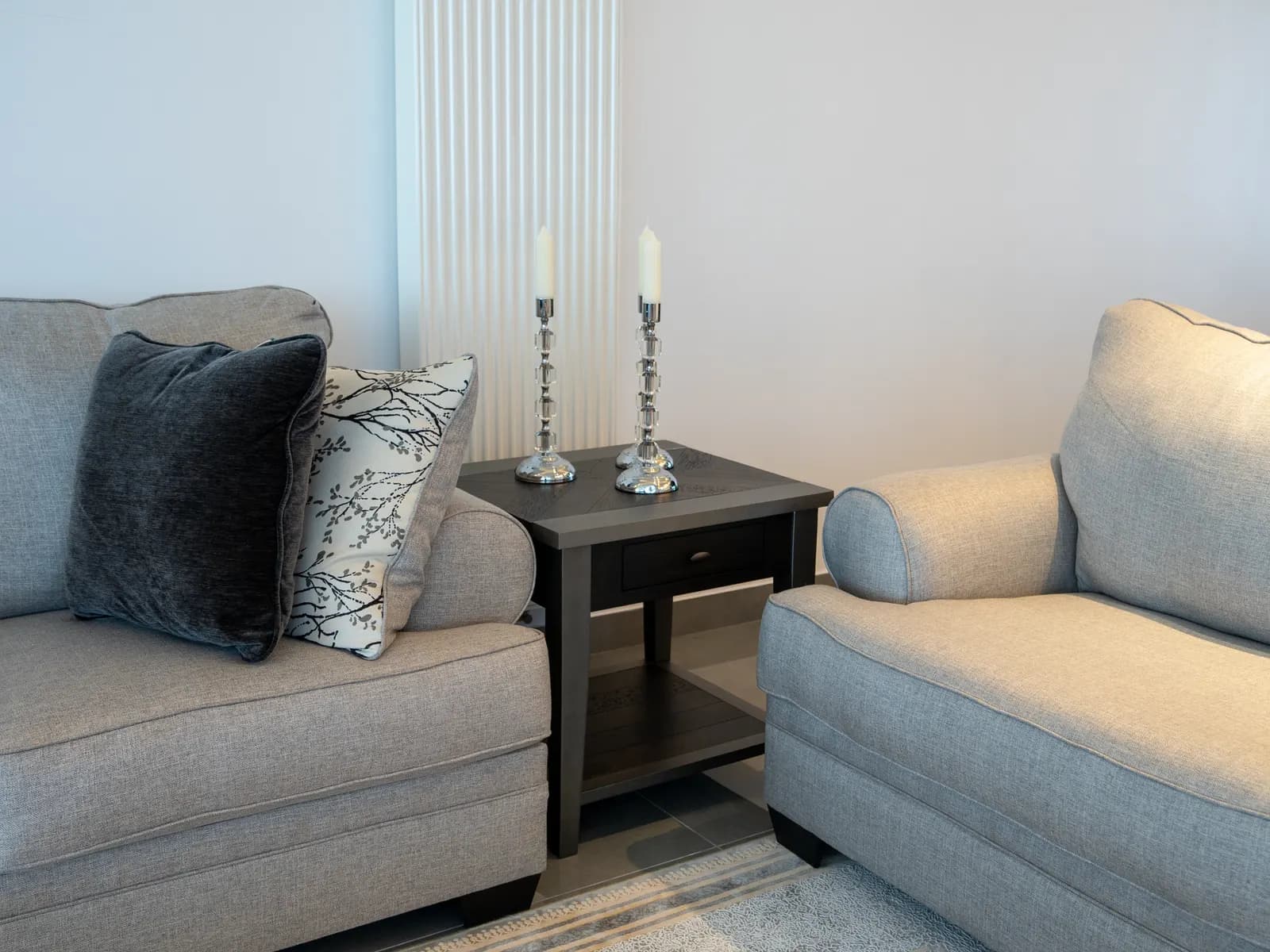 Cozy minimalist living room featuring gray sofas, wooden table, and decorative candles.