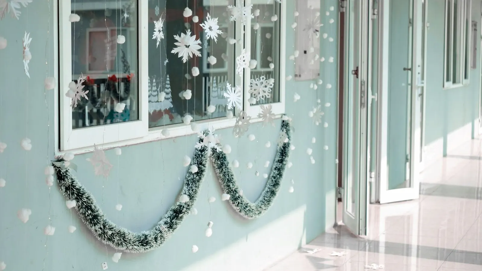 Apartment window decorated with white snowflake gel clings and a small battery string light
