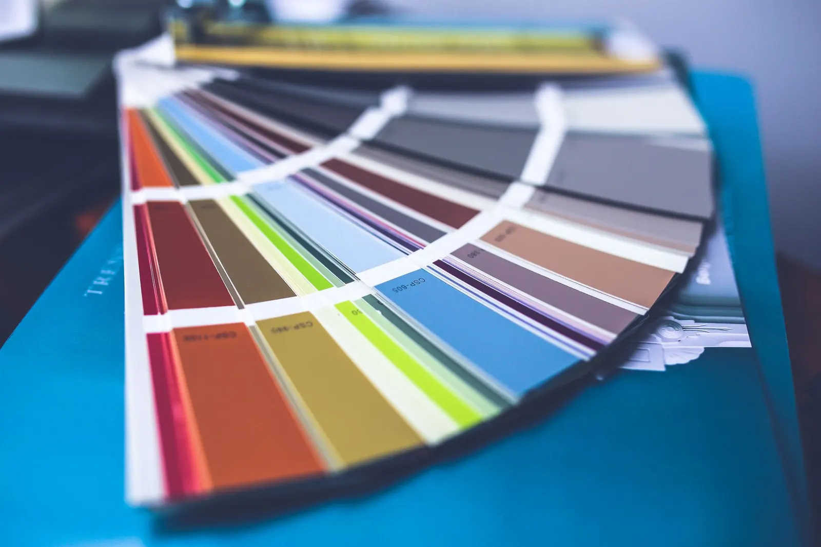 Fan of paint swatches in soft green, smoky blue, terracotta and brown on a wooden table