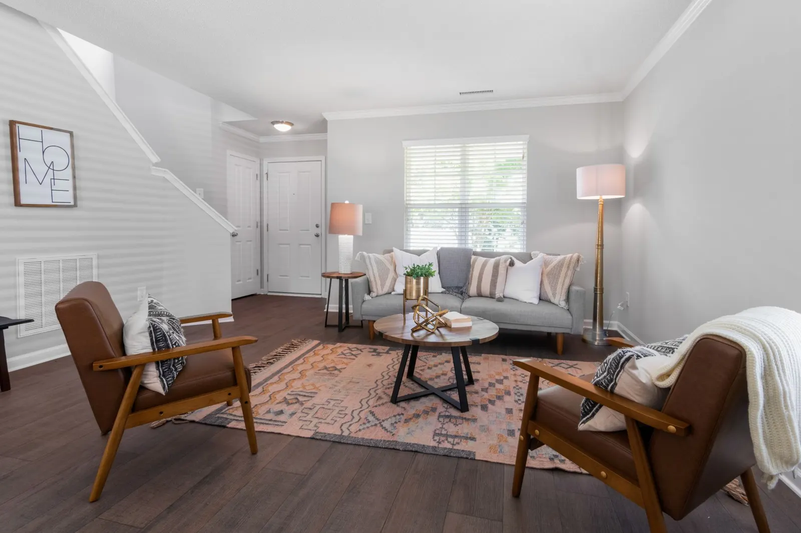 Sleek living room design featuring a sofa, chairs, lamps, and decorative touches.