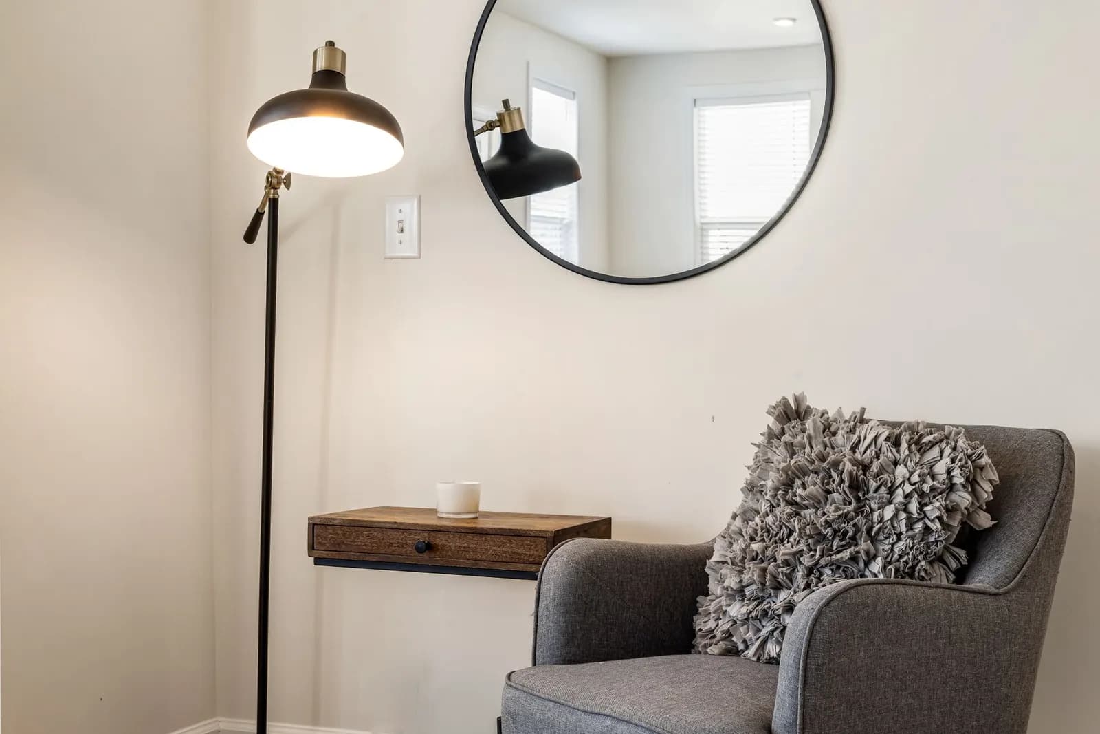 Comfortable corner with armchair, wooden shelf, and lamp in a modern living room.
