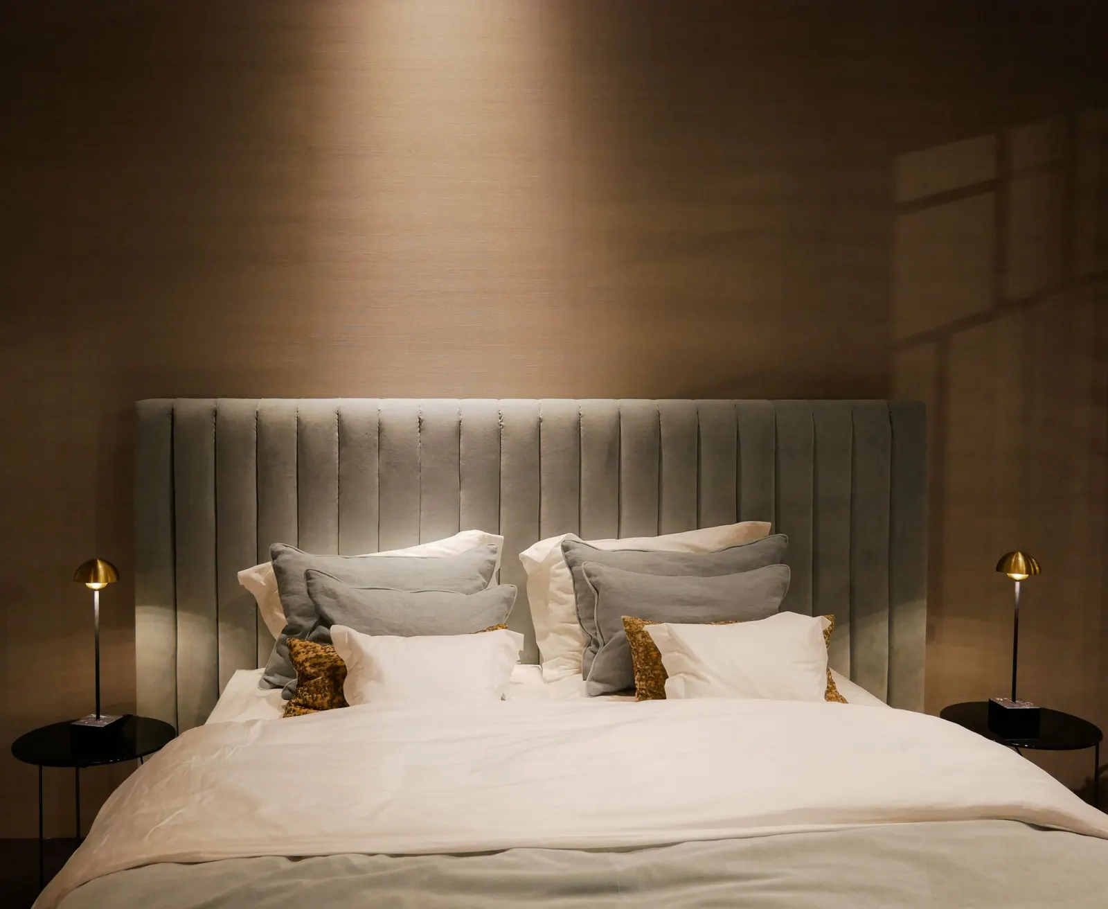 Neatly made bed with white percale bedding, a rust throw and matching ceramic lamps on two nightstands