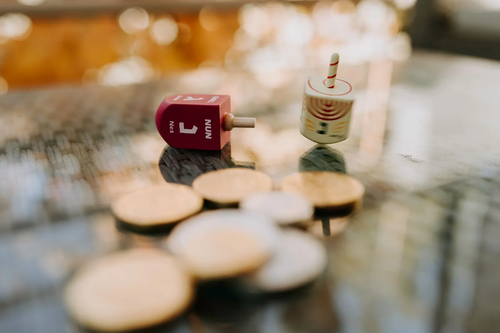 Wooden dreidels and gold and silver chocolate coins scattered on a blue table runner