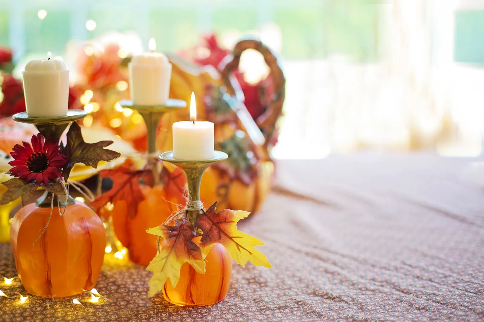Thanksgiving table for six with a burlap runner, faux pumpkins, glass vases and flameless pillar candles