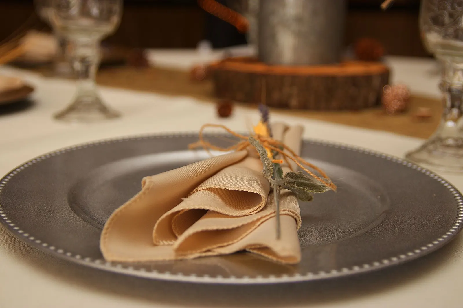 Folded napkin tied with jute twine and a kraft name tag on a white dinner plate