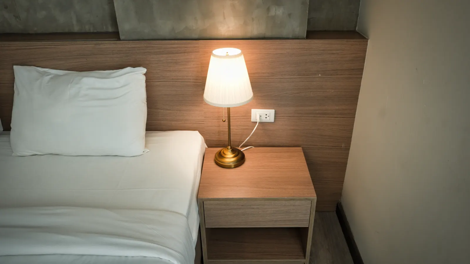 Painted wood nightstand with brass knobs, a thrifted lamp and glass vases styled against a cream wall