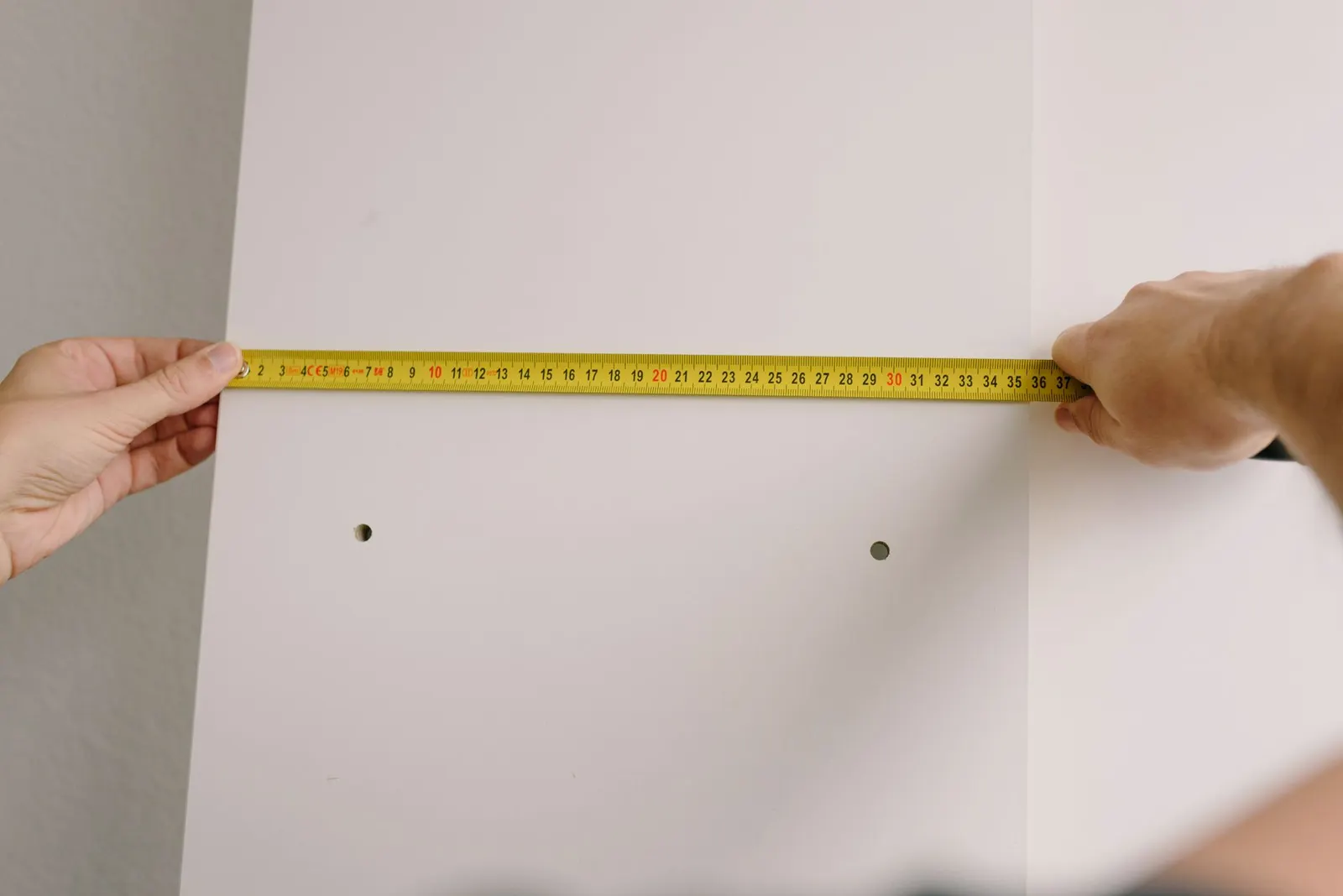Tape measure stretched across an empty apartment doorway with a wood floor and white walls