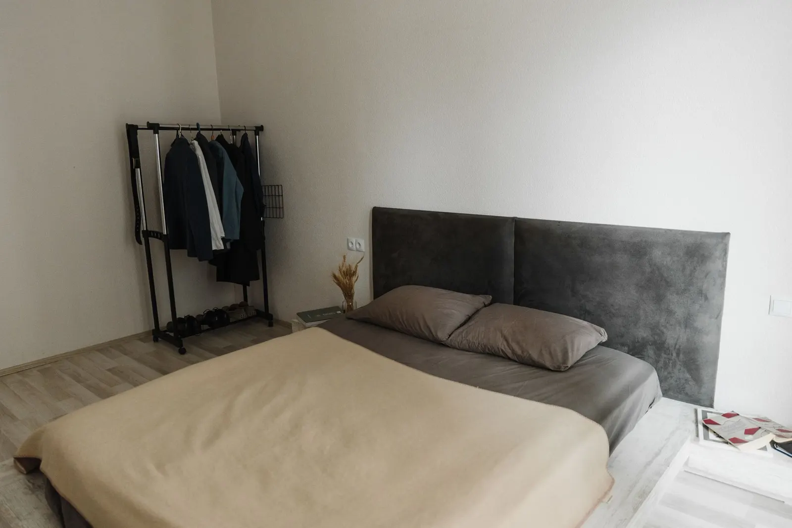 Simple bedroom with a metal platform bed, white sheets, a gray comforter and a small lamp on a crate