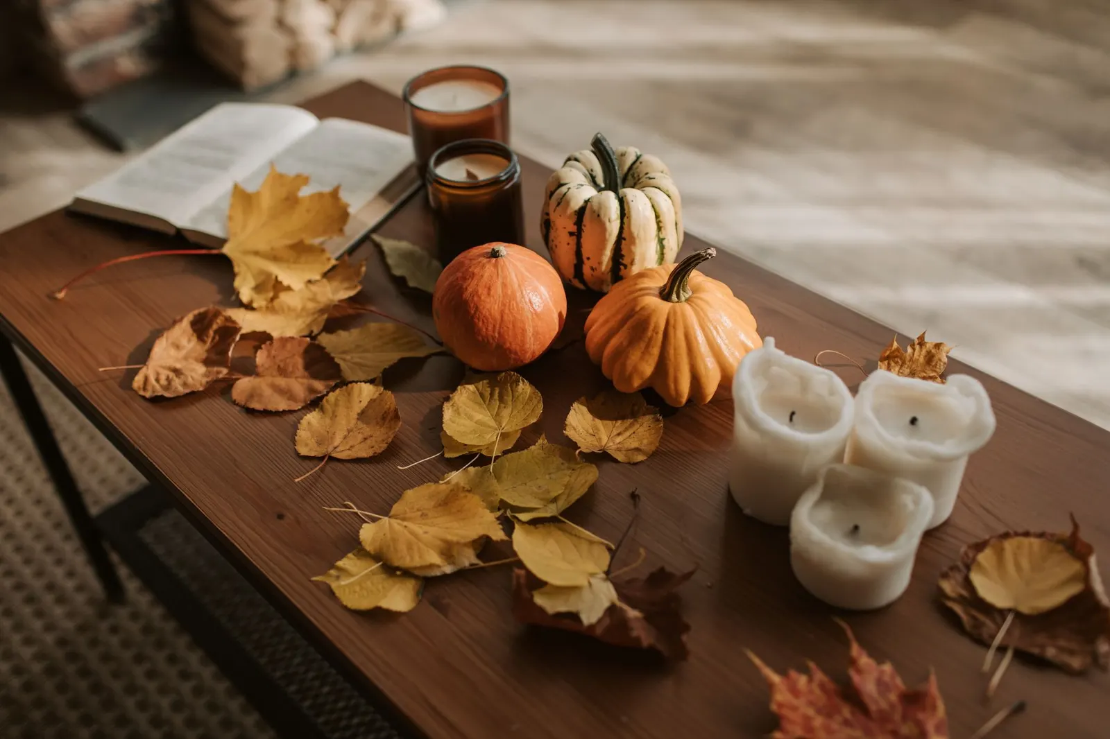 Low coffee table set for a casual fall dinner with kraft paper, mini pumpkins and glowing candles