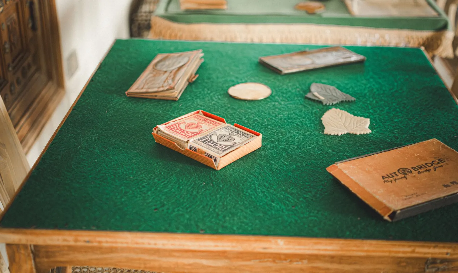 Playing cards and score pads on a green felt card table with a wooden edge