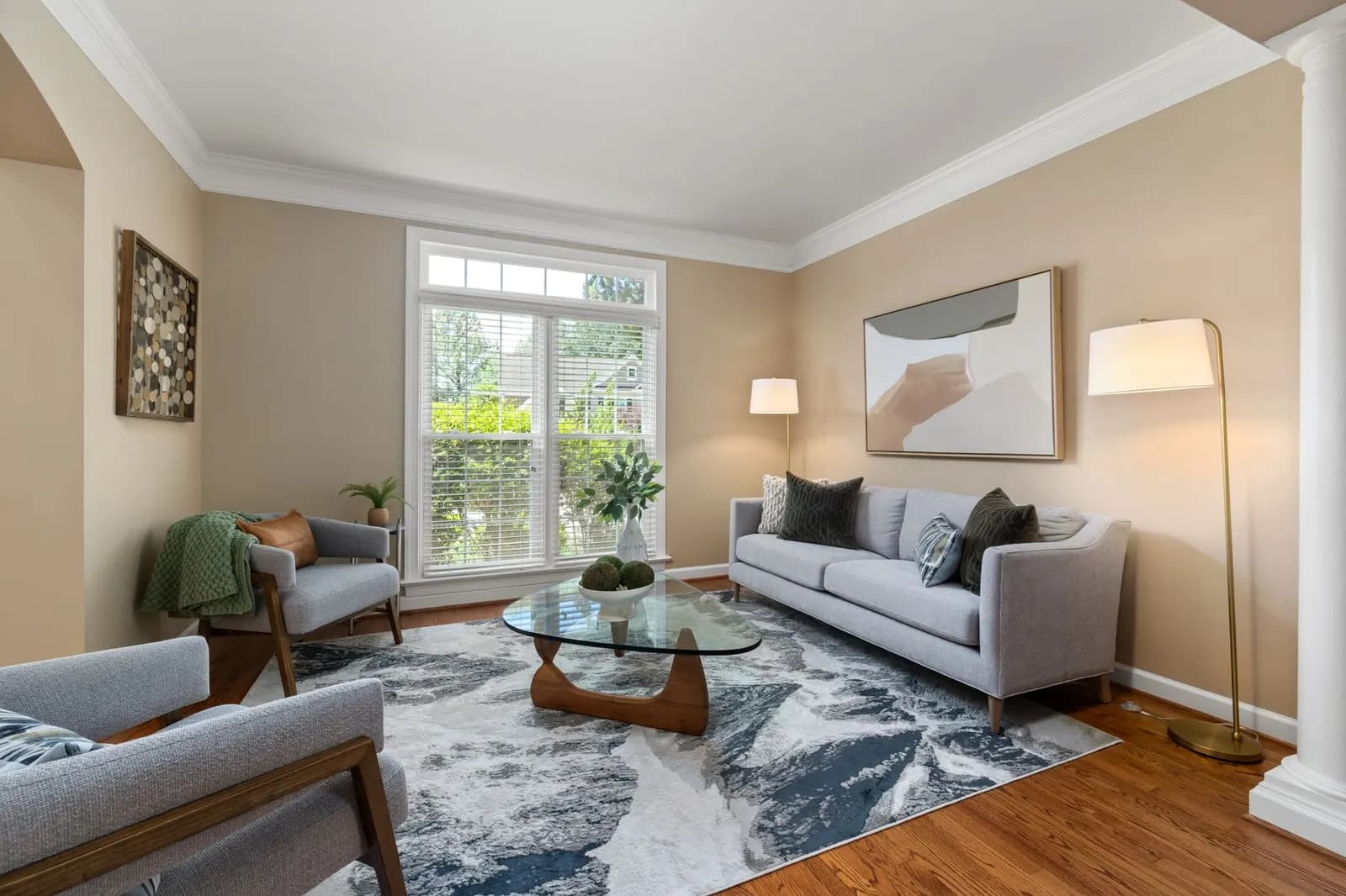 Small apartment living room on a gray day with white sheer curtains, a pale rug and a glowing floor lamp