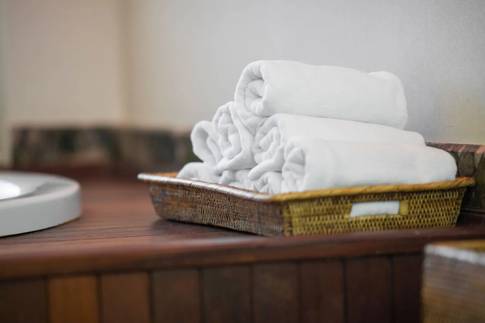 Rolled white towels in a woven tray