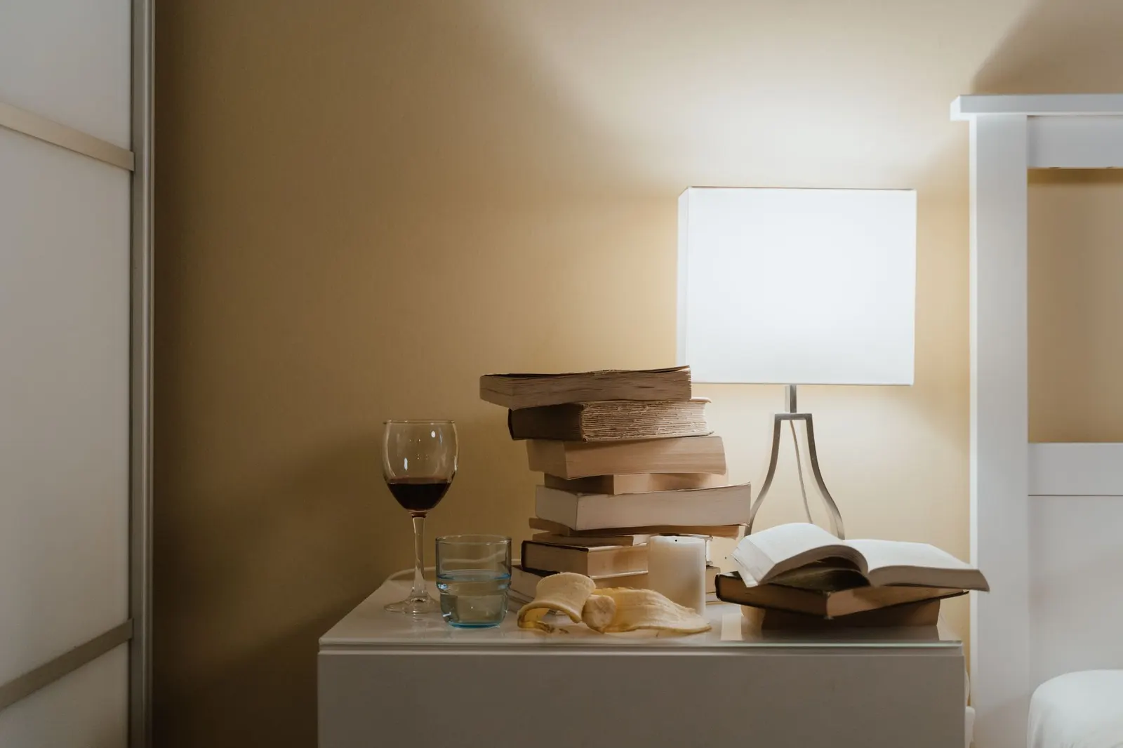 Bedside table with a white table lamp and a stack of books in a calm bedroom