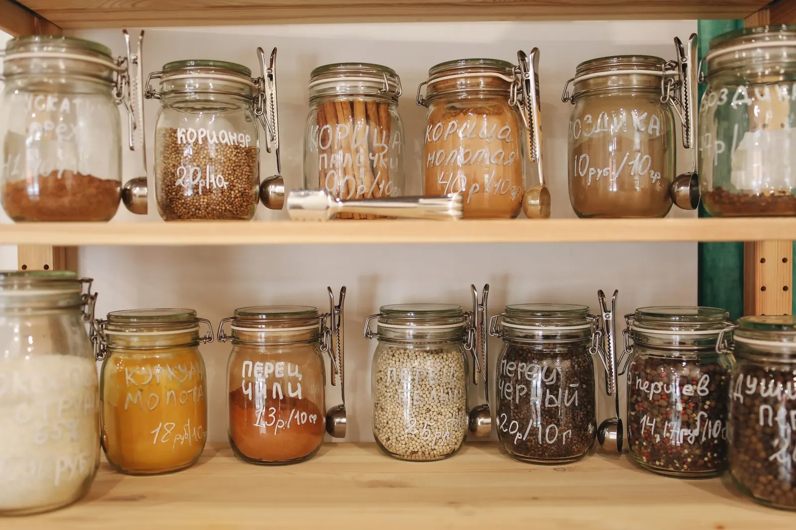 Tidy pantry shelves with clear bins, glass jars, woven baskets and handwritten labels in warm light