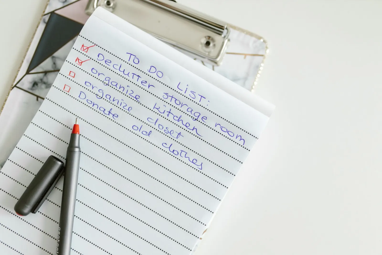 Handwritten to-do list on a clipboard with a pen