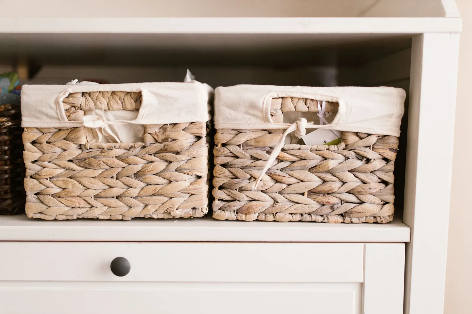 White shelf unit holding two woven storage baskets