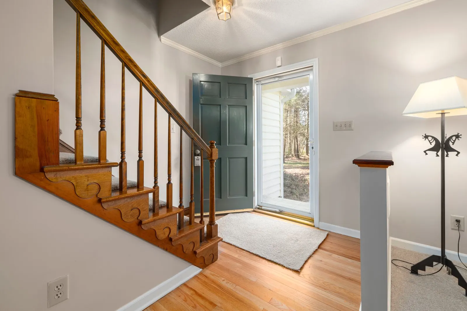 Entry hallway with a front door, a wood floor and a small rug by the stairs