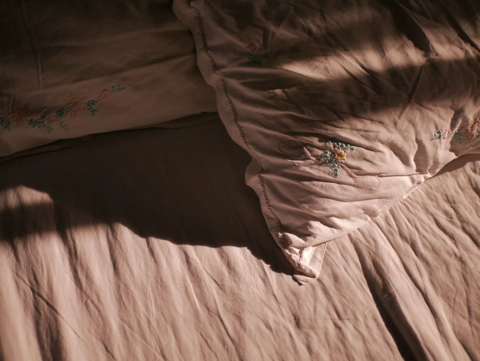 Bed layered with flannel sheets, a wool blanket and a knit throw in neutral tones