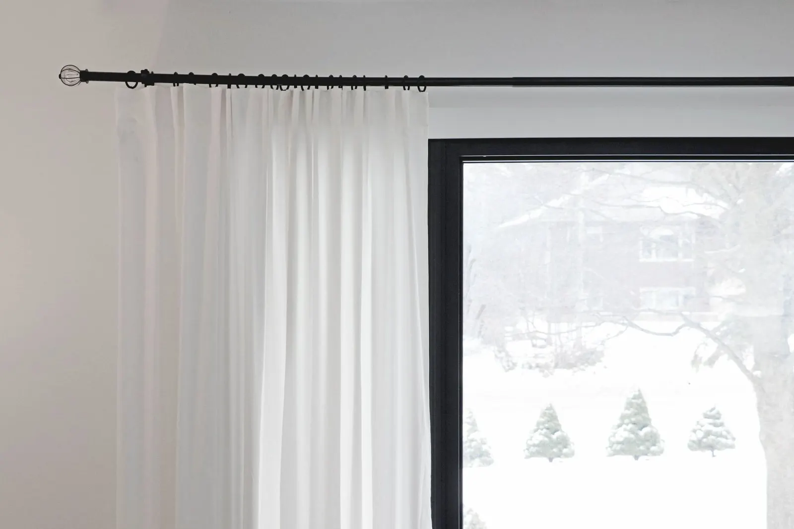 Floor-length cream lined curtains drawn across a window at night in a cozy bedroom