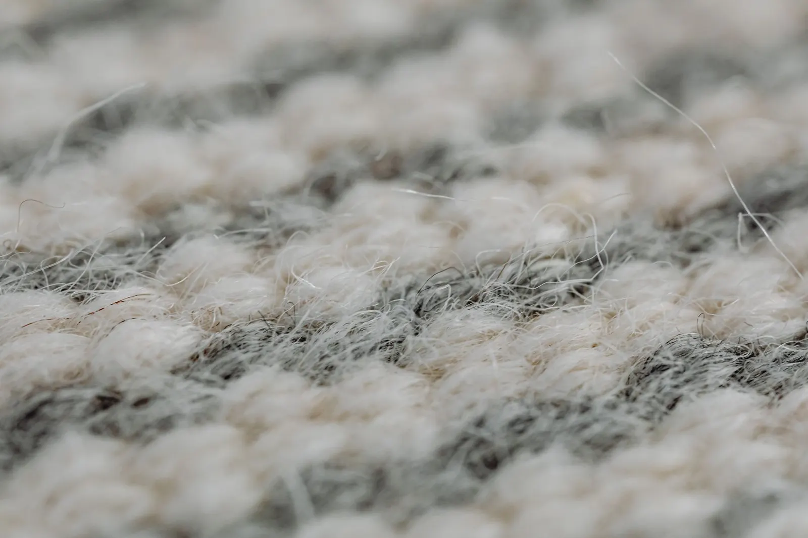 Thick wool area rug on a wood floor beside a sofa with a knit throw