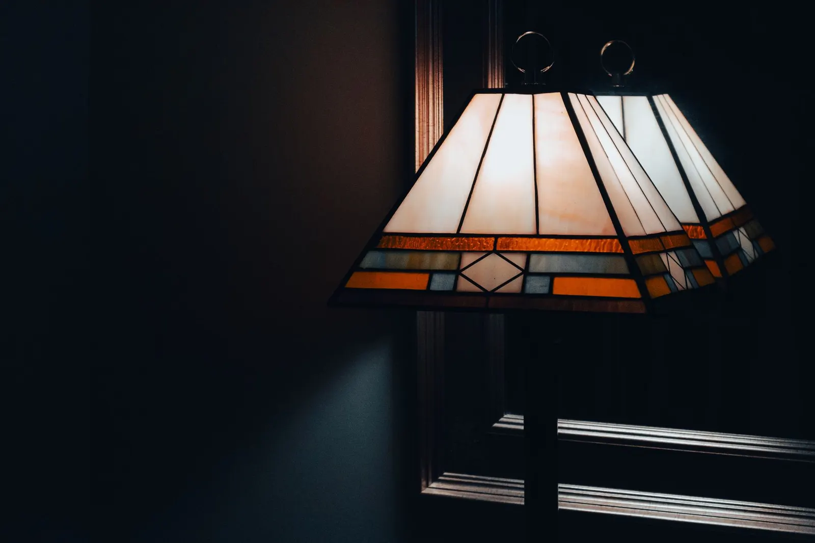 Art deco style lamp reflects in a mirror, creating a warm and atmospheric feel.