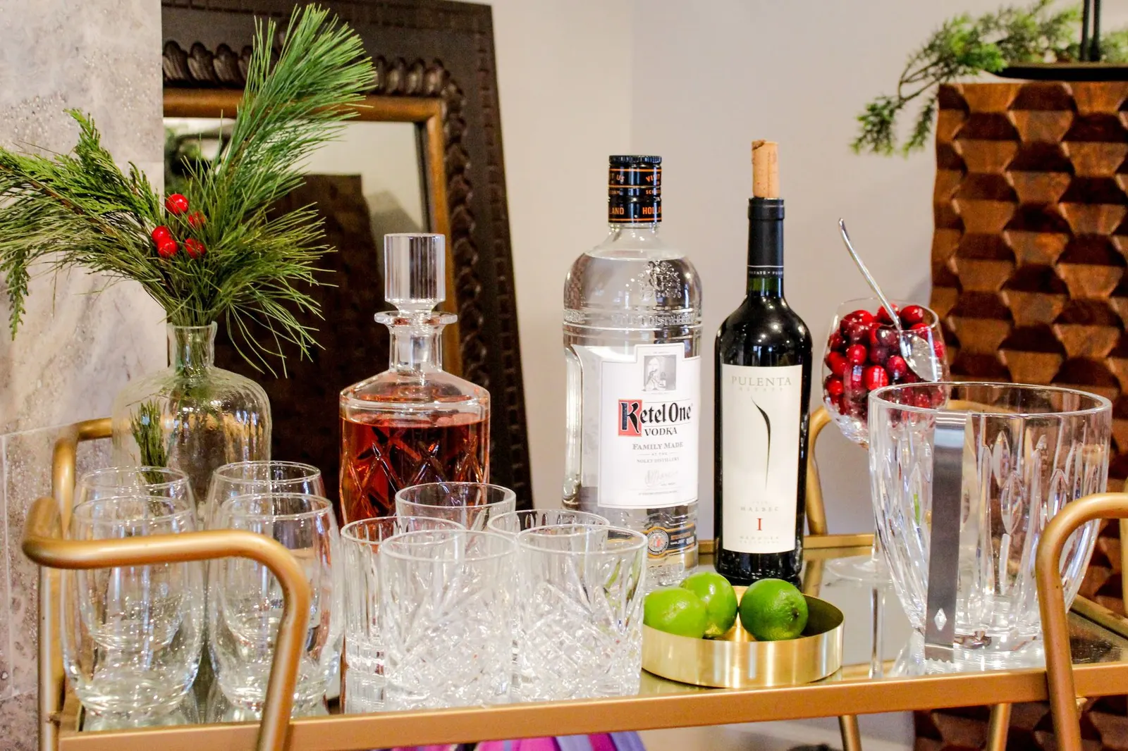 Elegant holiday bar cart setup with spirits, glasses, and festive decor.