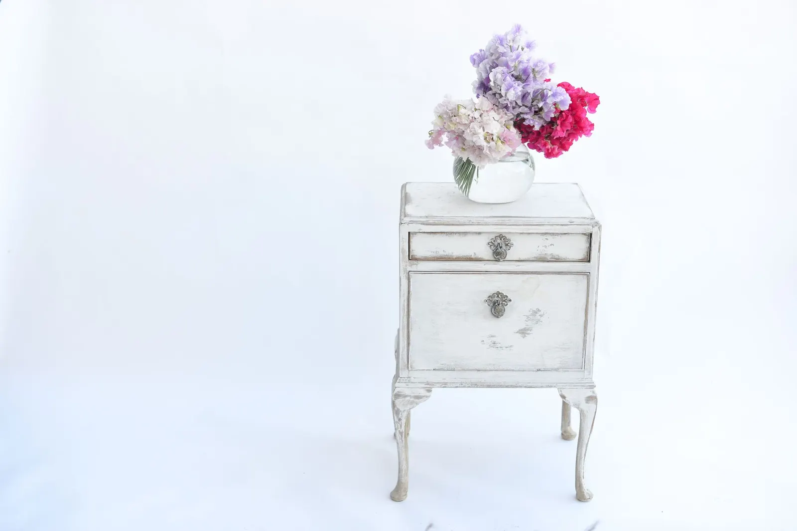 Elegant vintage nightstand with a colorful flower bouquet, perfect for classic decor themes.