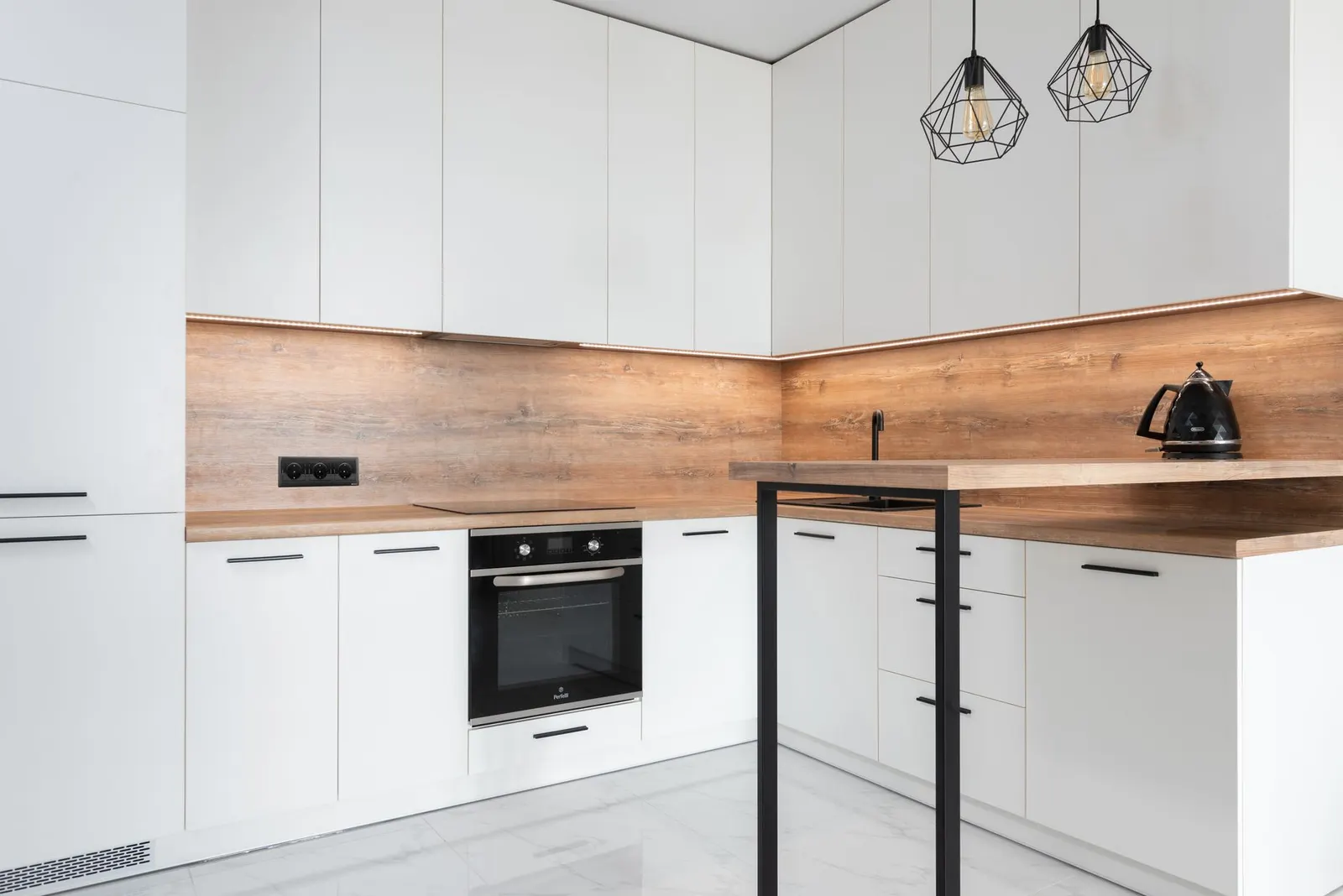 White kitchen cabinets with new brass knobs and a small rolling cart holding plants and jars