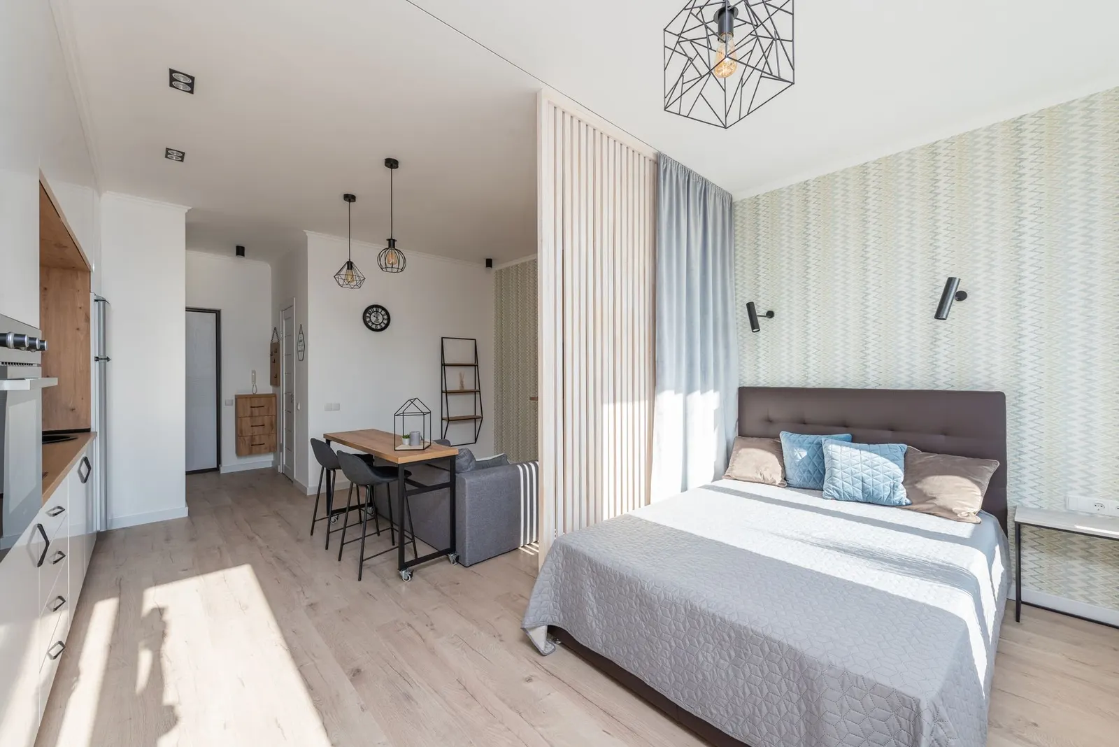 Studio apartment with a rug defining the living area and a bookcase separating the bed