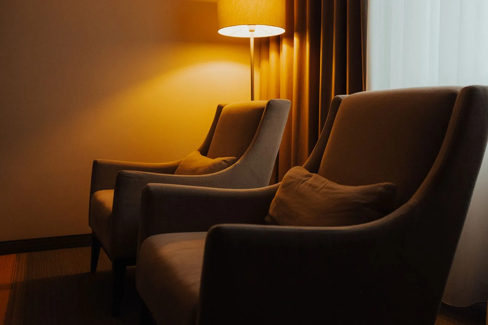 A cozy indoor setting featuring two armchairs and a warm lamp, perfect for relaxation.