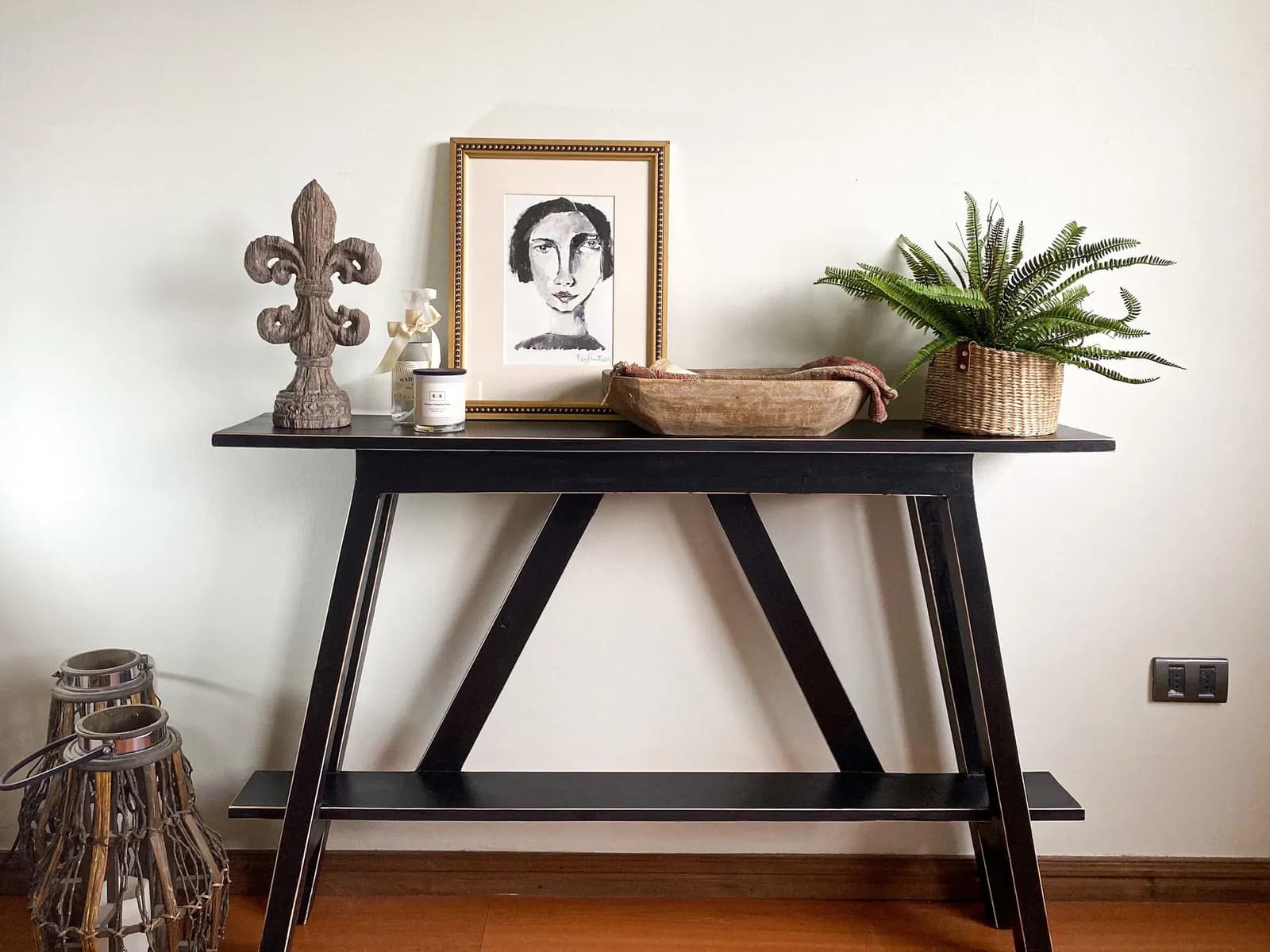 Console table with a jute runner, three glass vases, a wood tray, greenery garland and LED candles
