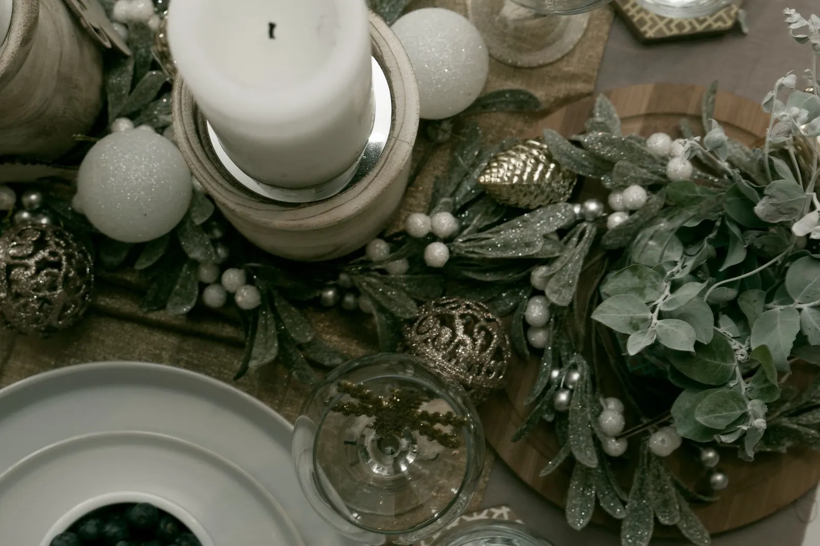 Dining table with a neutral runner, evergreen sprigs, glass vases and flameless pillar candles