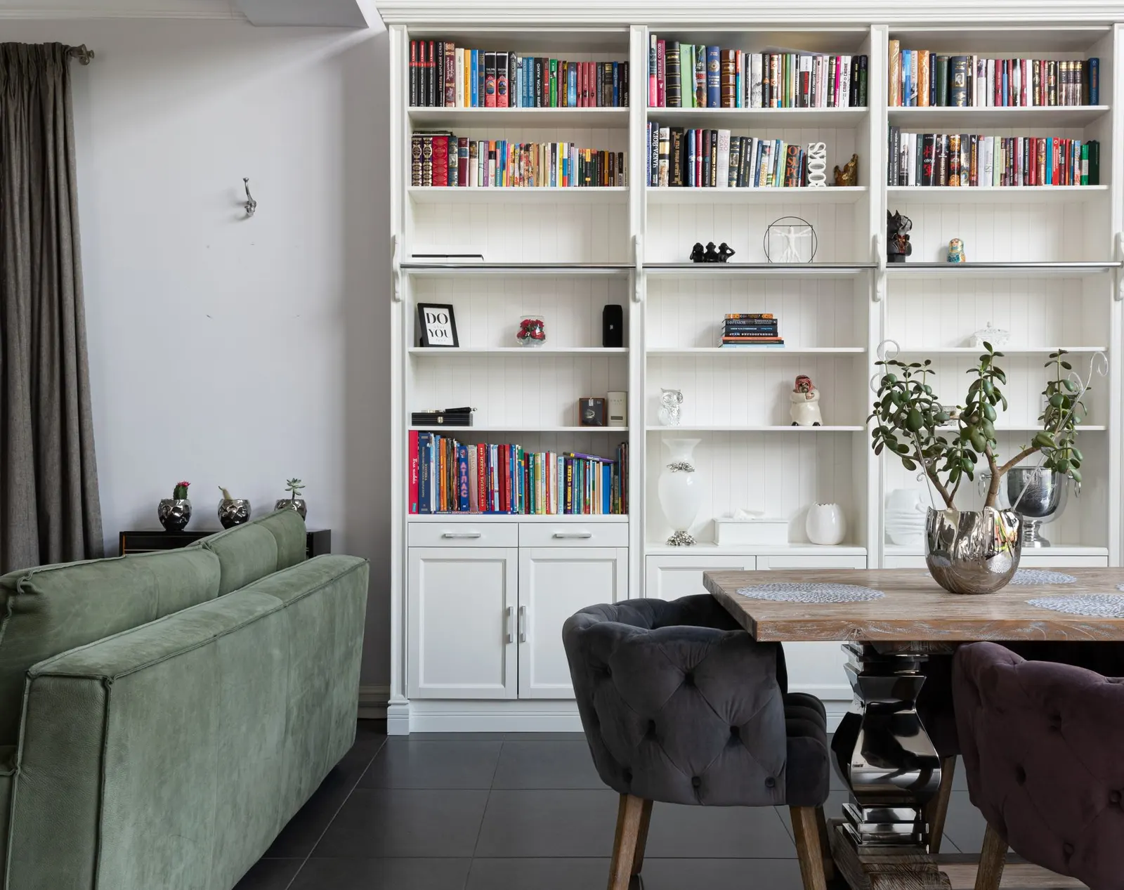 Elegant modern living room with bookcase, plush sofa, and decorative plants.
