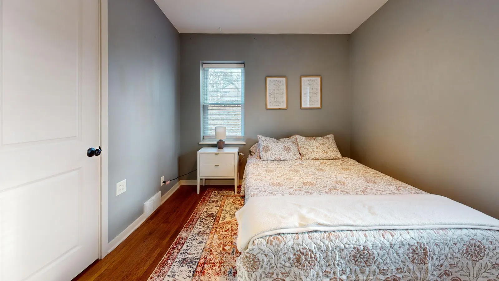 A serene minimalist bedroom with cozy bedding and natural light from a window.