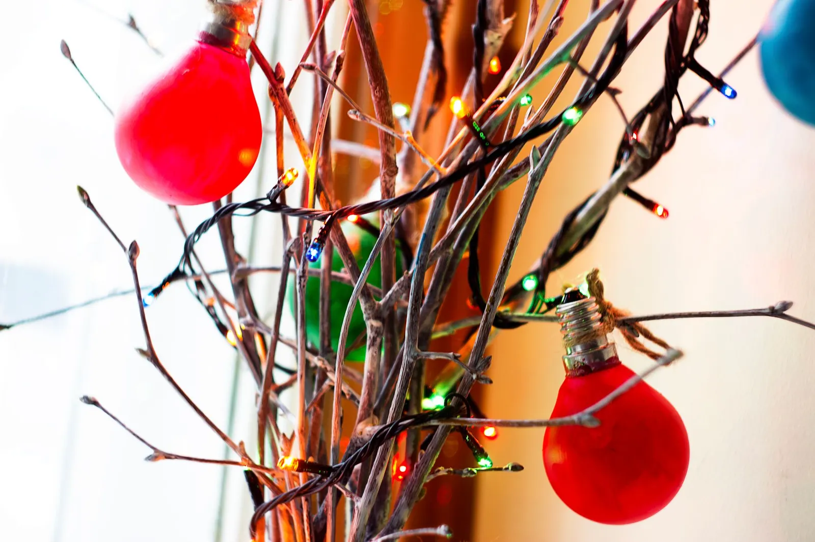 Close-up of colorful Christmas lights and decorations on bare branches, creating festive decor.